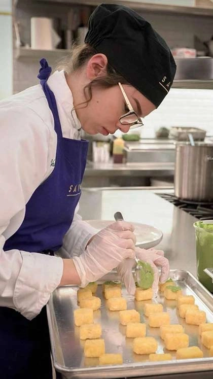 Student in the kitchen preparing food at Savor restaurant on the campus of The Culinary Institute of America in the Pearl District of San Antonio, Texas.